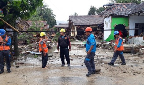 Petugas sedang memperbaiki kabel listrik di Anyer yang terkena tsunami, Ahad (23/12).