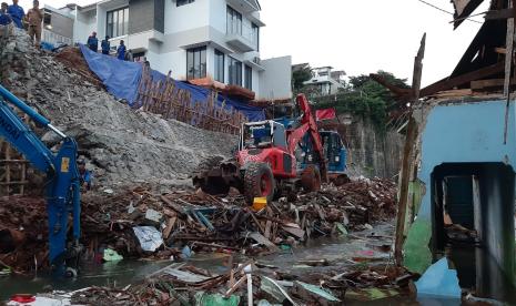 Petugas sedang mengangkat reruntuhan tebing yang menutup badan sungai di Jalan Damai RT 04/RW 02, Kelurahan Ciganjur, Jagakarsa, Jakarta Selatan, pada Senin (12/10). Turap kayu juga mulai dipasang di tebing itu guna mencegah longsor susulan.