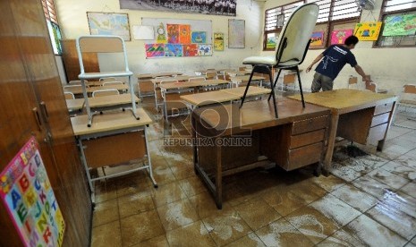 Petugas sekolah membersihkan ruang kelas yang terendam banjir di SD 4 Penjaringan, Jakarta Utara, Selasa (10/2).