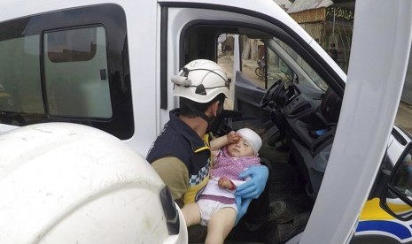 Petugas sipil membawa seorang bayi usai serangan rudal di jalanan Kota Nairab, di barat Idlib, Suriah, Ahad (7/4). 