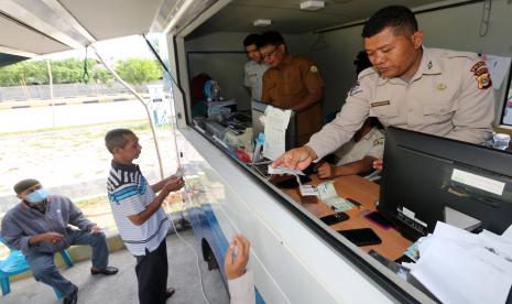 Petugas Sistem Administrasi Manunggal Satu Atap (SAMSAT) keliling melayani warga yang membayar pajak kendaraan bermotor di Banda Aceh, Aceh.  Masyarakat diingatkan terkait regulasi penghapusan data untuk kendaraan bermotor yang pajaknya sudah mati selama dua tahun. Tim Pembina Samsat Nasional yang terdiri dari Jasa Raharja, Korlantas Polri, dan Kemendagri saat ini tengah mensosialisasikan implementasi Undang-undang Nomor 22 Tahun 2009 tentang Lalu Lintas dan Angkutan Jalan, khususnya Pasal 74 tentang penghapusan data kendaraan bermotor yang mati pajak selama dua tahun.