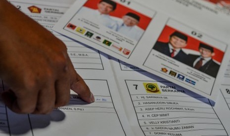 Petugas sortir dan lipat surat suara menunjukan surat suara yang terdapat percikan tinta