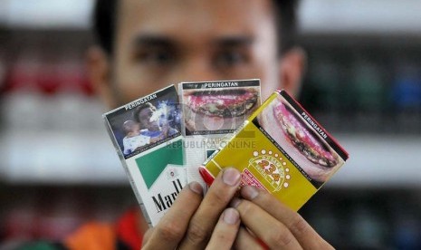 Petugas supermarket menunjukan sejumlah rokok yang sudah dilengkapi peringatan bergambar akan bahaya merokok di Jakarta, Senin (23/6).