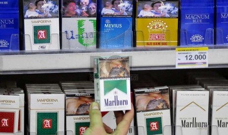 Petugas supermarket menunjukan sejumlah rokok yang sudah dilengkapi peringatan bergambar akan bahaya merokok di Jakarta, Senin (23/6).