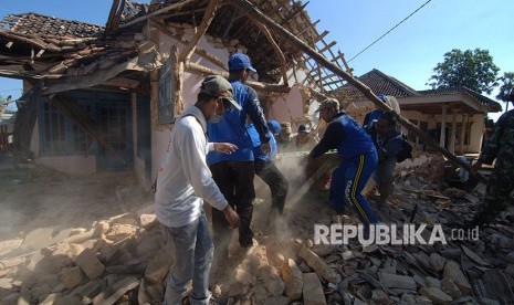 Petugas Tagana dibantu anggota TNI membersihkan puing rumah yang ambruk akibat gempa yang melanda Desa Bula'an, Sumenep, Jawa Timur, Kamis (14/6)