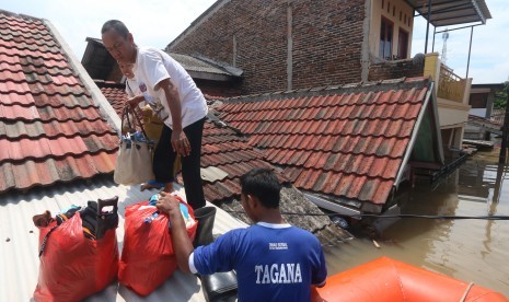 Petugas Taruna Siaga Bencana (TAGANA) Kota Tangerang membantu mengevakuasi warga korban banjir di perumahan Total Persada, Tangerang, Banten, Senin (14/11).