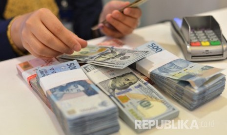 Petugas teller menghitung pecahan uang dolar AS. ilustrasi