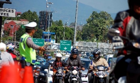 Petugas tengah mengatur arus lalu lintas yang tengah macet.