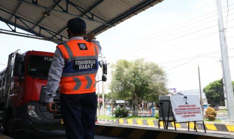 Petugas tengah mengatur kendaraan truk memasuki Jembatan Timbang.