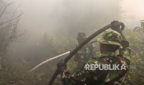 Petugas TNI berusaha memadamkan kebakaran lahan di tengah pekatnya asap ketika terjadi kebakaran lahan gambut di Pekanbaru, Riau, Jumat (2/8/2019).