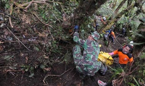 Petugas TNI dan sejumlah relawan mengevakuasi korban jatuhnya pesawat Sukhoi Superjet 100 ke Puncak I Gunung Salak, Kabupaten Bogor, Jawa Barat, Ahad (13/5).