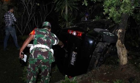 Petugas TNI melihat mobil anggota polisi yang terbalik di TKP penembakan polisi di Graha Raya, Pondok Aren, Tangerang Selatan, Jumat (16/8). 