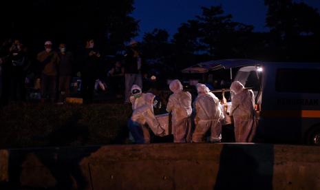 Petugas yang mengenakan APD membawa peti berisi jenazah dengan protokol COVID-19 di TPU Srengseng Sawah, Jakarta, Kamis (21/1/2021). TPU Srengseng Sawah yang baru sepekan dibuka untuk pemakaman dengan protokol COVID-19 dan menyediakan 541 liang lahat hampir penuh karena tingginya jumlah kematian akibat COVID-19.