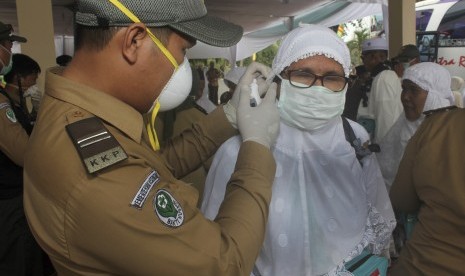 Peugas kesehatan memeriksa suhu tubuh seorang haji dengan alat pengukur saat kedatangan jamaah haji di Asrama Haji Provinsi Bengkulu, Kamis (8/10).