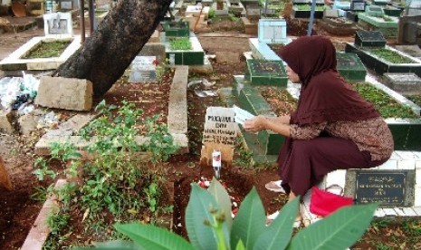 Peziarah berdoa di depan makam sanak saudaranya.