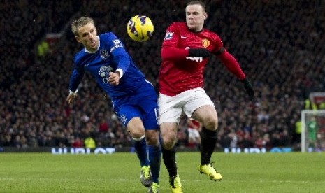 Phil Neville (kiri) berebut bola dengan Wayne Rooney.