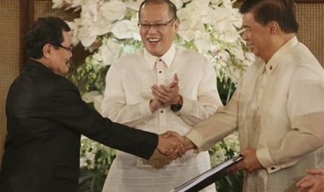 Presiden Filipina Benigno Aquino III (tengah) menyaksikan ketua tim perunding Front Pembebasan Islam Moro (MILF) Mohagher Iqbal (kiri) berjabat tangan dengan Presiden Senat Franklin Drilon di Manila, Filipina.