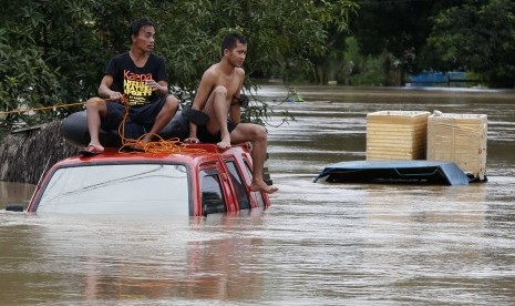 PHILIPPINES - Residents sit on the roof of a vehicle submerged in heavy flooding brought by tropical depression 