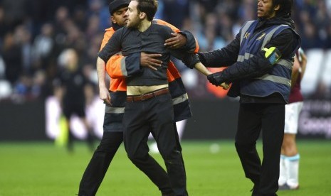 Pihak keamanan menahan seorang fan West Ham yang masuk ke lapangan Stadion London saat laga melawan Burnely, Sabtu (10/3).