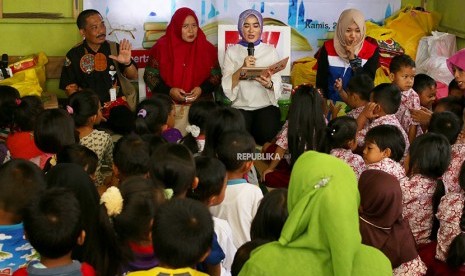 Plt Direktur Utama Pertamina Nicke Widyawati (kedua kanan) membacakan dongeng untuk anak-anak di Rumah Baca Banyu Ilmi, Kampung Baru, Balikpapan, Kalimantan Timur, Kamis (26/4).