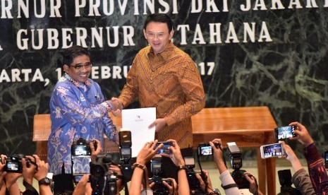 Plt Gubernur DKI Jakarta Soni Sumarsono (kiri) menyerahkan laporan nota singkat kepada Gubernur Petahana Basuki Tjahaja Purnama di Balai Kota Jakarta, Sabtu (11/2). 