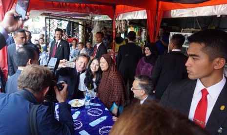 PM Inggris David Cameron melakukan selfie dan memakan pisang goreng di pedagang kaki lima di depan Masjid Sunda Kelapa, Selasa (28/7).