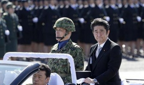 PM Jepang Shinzo Abe (mengenakan jas) melakukan inspeksi terhadap pasukan Bela Diri Jepang dalam peringatan Hari Bela Diri di Pangkalan Asaka, Tokyo.