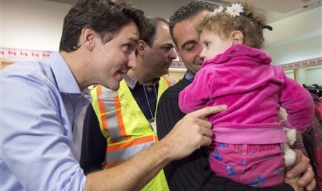 PM Kanada Justin Trudeau (kiri) menyapa pengungsi Suriah, Madeleine Jamkossian (kanan) dan ayahnya Kevork Jamkossian saat tiba di Bandara Internasional Pearson di Toronto, Jumat (11/12).  