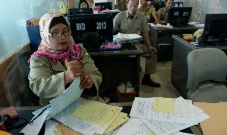 PNS sedang menyelesaikan berkas administrasi di kantor.