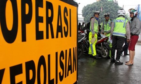 Polantas membuat surat tilang untuk pengendara motor ketika berlangsungnya Operasi Patuh Jaya di kawasan Kemanggisan Utama, Jakarta Barat, JumaT (5/7). Oparasi tersebut digelar untuk meningkatkan ketertiban dan kepatuhan berlalu lintas