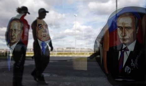 Police are reflected in the window of a shop displaying traditional nesting dolls with images of Russian President Vladimir Putin (right), Prime Minister Dmitry Medvedev (center) and French President Francois Hollande at the sea port in St. Petersburg Sept