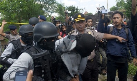 Police holds a suspected terrorist (center) after raid in Solo, Central Java, on Thursday.