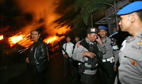 Police officers guard outside Tanjung Gusta prison that was partially set ablaze by inmates during a prison riot in Medan, North Sumatra, Indonesia, Thursday, July 11, 2013. President Susilo Bambang Yudhoyono instructs all penitentiaries in Indonesia to ti