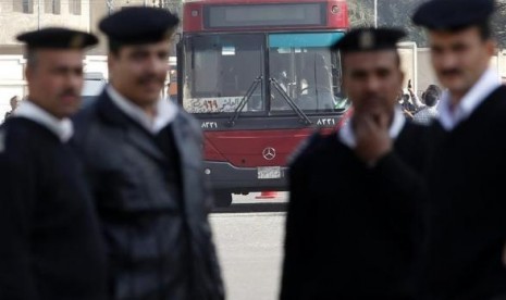 Police officers stand guard in front of a damaged bus after a bomb blast near the Al-Azhar University campus in Cairo's Nasr City district December 26, 2013. 