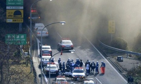 Police vehicles are parked at the entrance as smoke billows out of the Sasago Tunnel on the Chuo Expressway in Koshu, Yamanashi Prefecture, central Japan, Sunday morning, Dec. 2, 2012. A part of the tunnel collapsed Sunday morning, possibly involving sever