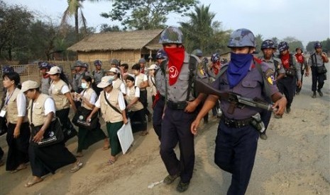 Policemen covers their faces to protect from the dust as they walk with census enumerators at Thae Chaung village in Sittwe, Rakhine State, western Myanmar, Tuesday, April 1, 2014. 