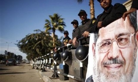 Policemen stand guard near a poster outside the constitutional court put up by supporters of Egyptian President Mohamed Mursi as they stage a sit-in, in Cairo December 23, 2012.   