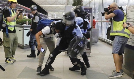 Polisi antihuru-hara Hong Kong menahan seorang demonstran di Bandara Internasional Hong Kong, Selasa (13/8).