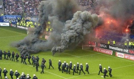 Polisi antihuru-hara memasuki lapangan setelah fan Hamburg berbuat kerusuhan pada laga Bundesliga lawan Borussia Muenchengladbach pada Sabtu (12/5).