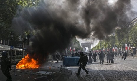 Polisi antihuru-hara Prancis berjaga di Champs-Elysees saat bentrok dengan pengunjuk rasa ketika parade hari Bastille, Ahad (14/7).