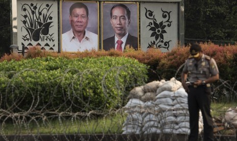 Polisi berdiri di dekat foto Presiden Joko Widodo dan Presiden Filipina Rodrigo Duterte yang dipajang di seberang Istana Merdeka, Jakarta, Kamis (8/9). 