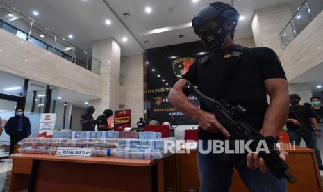 Polisi berjaga di dekat barang bukti saat rilis pengungkapan kasus kejahatan siber di Bareskrim Mabes Polri, Jakarta, Senin (5/10/2020). Bareskrim Polri berhasil menangkap sindikat pembobol akun nasabah bank dan aplikasi transportasi daring Grab dengan kerugian mencapai Rp21 miliar.