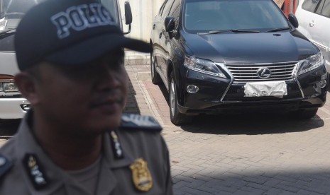 Polisi berjaga di depan mobil Toyota Lexus yang diamankan dari operasi tangkap tangan (OTT) KPK di Gedung KPK, Jakarta, Jumat (1/4). 