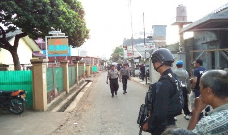 Polisi berjaga di lokasi penggerebakan sebuah rumah di Bintara Jaya, Bekasi, Sabtu (10/12). Di rumah bertingkat tiga bercat biru dan pink ditemukan benda diduga bom.