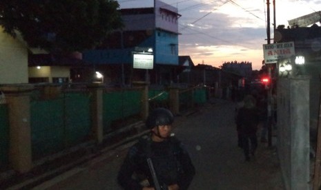 Polisi berjaga di lokasi penggerebakan sebuah rumah di Bintara Jaya, Bekasi, Sabtu (10/12). Di rumah bertingkat tiga bercat biru dan pink ditemukan benda diduga bom.