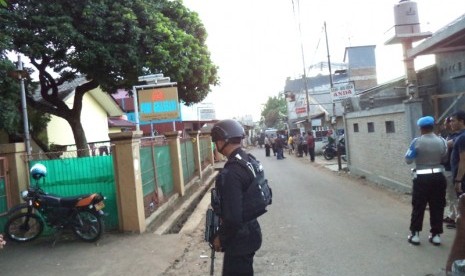 Polisi berjaga di lokasi penggerebakan sebuah rumah di Bintara Jaya, Bekasi, Sabtu (10/12). Di rumah bertingkat tiga bercat biru dan pink ditemukan benda diduga bom.