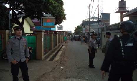 Polisi berjaga di lokasi penggerebakan sebuah rumah di Bintara Jaya, Bekasi, Sabtu (10/12). Di rumah bertingkat tiga bercat biru dan pink ditemukan benda diduga bom.