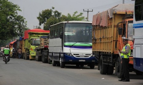   Polisi berjaga diantara kemacetan panjang kendaraan dari Serang menuju Jakarta yang macet total akibat diblokir buruh di gerbang Tol Jakarta-Merak KM-57, Ciujung, Serang, Banten, Selasa (3/12).  (Antara/Asep Fathulrahman)