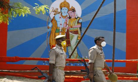 Polisi berjalan melewati gambar dewa Hindu Ram pada malam upacara peletakan batu pertama sebuah kuil yang didedikasikan untuk Ram di Ayodhya, India, Selasa, 4 Agustus 2020. Upacara peletakan batu pertama Rabu mengikuti keputusan Mahkamah Agung India November lalu yang mendukung pembangunan tersebut dari sebuah kuil Hindu di situs yang disengketakan di negara bagian Uttar Pradesh. Orang Hindu percaya bahwa dewa mereka, Ram, lahir di lokasi itu dan mengklaim bahwa Kaisar Muslim Babur membangun sebuah masjid di atas sebuah kuil di sana. Masjid Babri abad ke-16 dihancurkan oleh kelompok Hindu garis keras pada bulan Desember 1992, memicu kekerasan besar-besaran Hindu-Muslim yang menewaskan sekitar 2.000 orang.