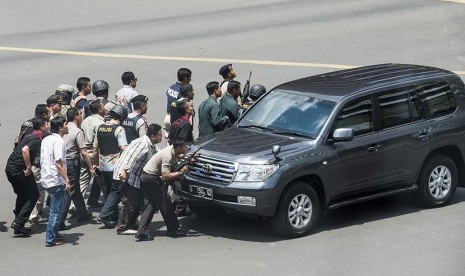 Polisi berlindung di balik mobil saat akan menyergap pelaku penyerangan kedai Starbuck di kawasan jalan Thamrin, Jakarta, Kamis (14/1).